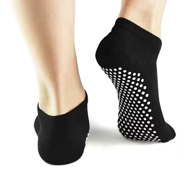 Custom black no-show grip socks with white silicone dots, shown worn on feet from behind for anti-slip traction.
